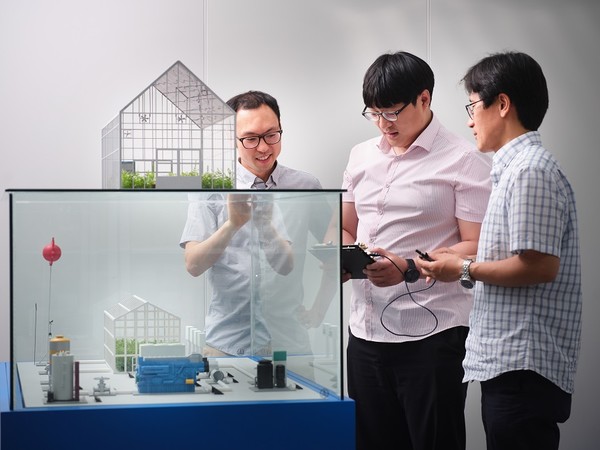 ETRI 연구진이 스마트팜 시스템 구축을 위해 스마트팜 디오라마를 보며 관련 사항을 논의하고 있다. [사진=ETRI]