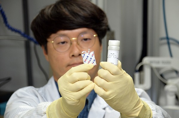 ETRI 연구진이 불소화황산화물계 난연 첨가제(우측)와 첨가제가 적용된 리튬이차전지(좌측)를 관찰하고 있다. [사진=ETRI]