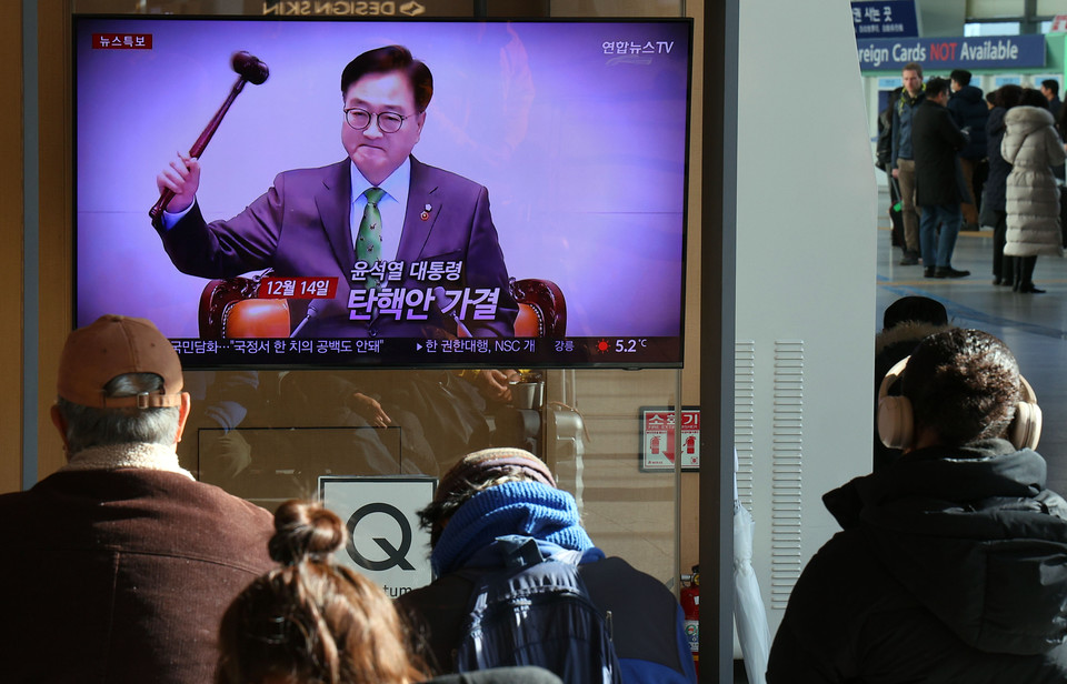 15일 서울역 대합실에서 시민들이 대통령 탄핵소추안 가결 관련 뉴스를 시청하고 있다. [사진=연합뉴스]