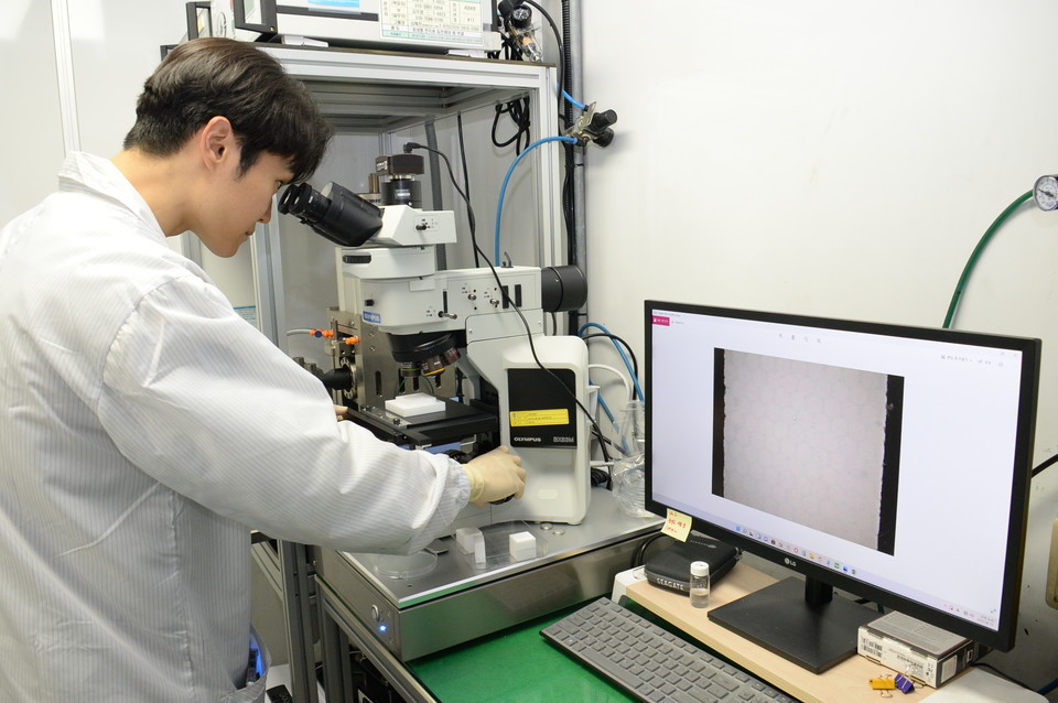 ETRI 연구진이 대면적 고체전해질막의 구조를 광학현미경을 통해 분석하고 있다. [사진=ETRI]